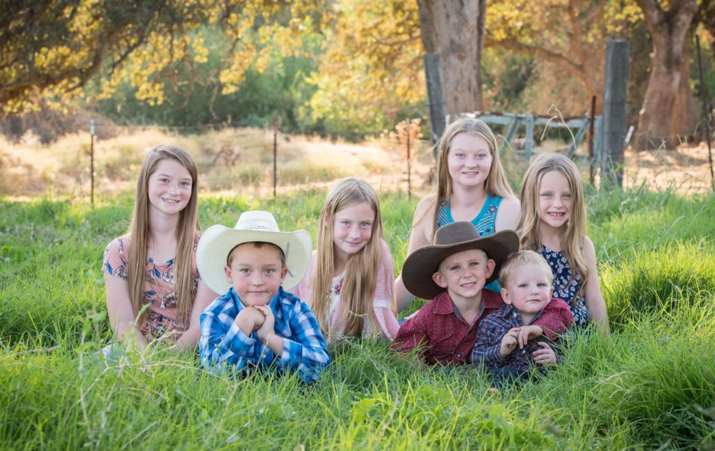 Portrait of seven children from several different families sitting and laying in the grass.