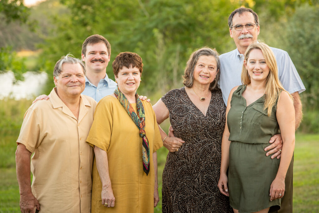 Portrait during an Omaha family session of six built by the young husband and wife with each of the young person's families separated in the middle, with the wife and her parents on the right and the husband and his parents on the left.