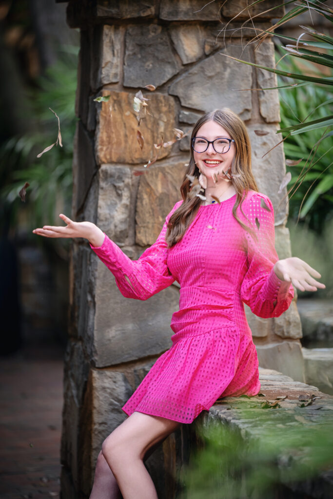 Portrait by A2I Photography with a young woman in a pink dress tossing leaves in the air.