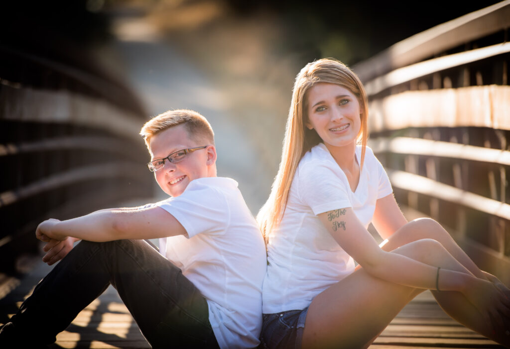 Brother and sister sitting on a bridge