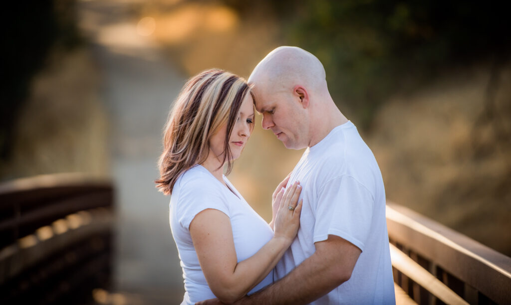 Gorgeous couple touching foreheads in a candid moment on a walking bridge