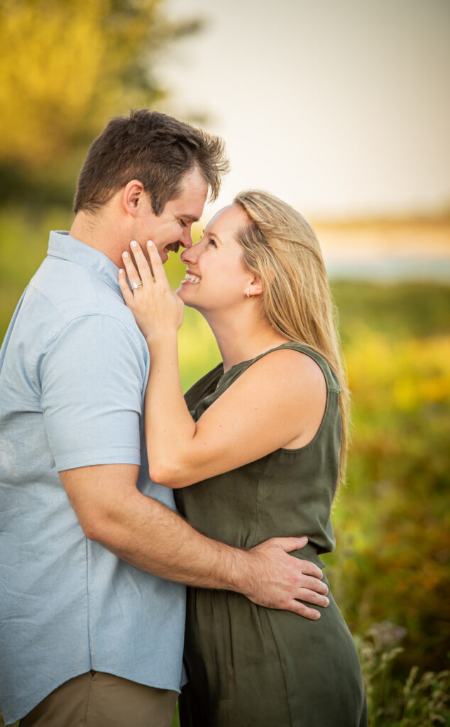 A newly engaged couple looking into each others eyes in front of the sunset 