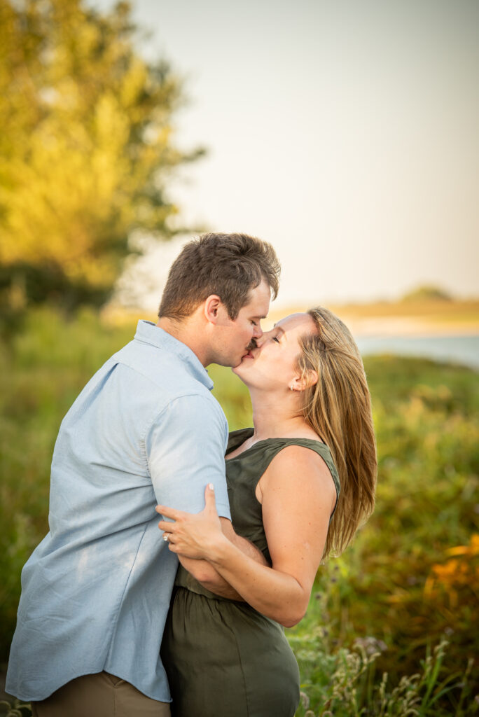 A newly engaged couple kissing in front of the sunset 