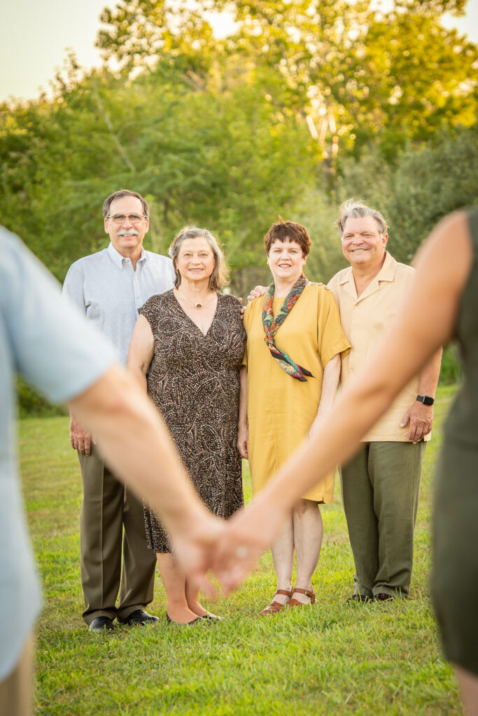 A newly engaged couple holding hands in front of their parents during an Omaha family session