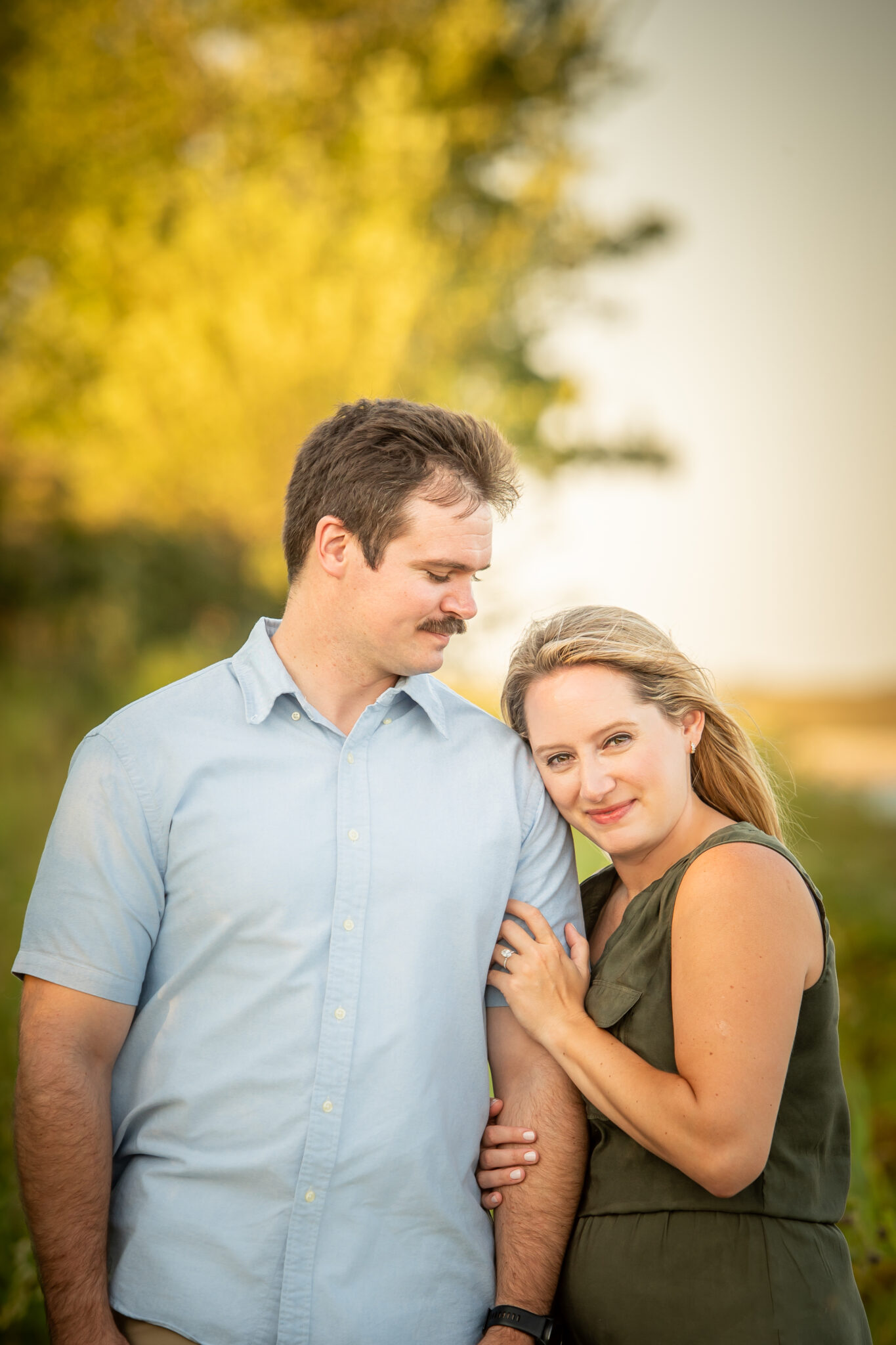 A newly engaged couple holding each other in front of the sunset