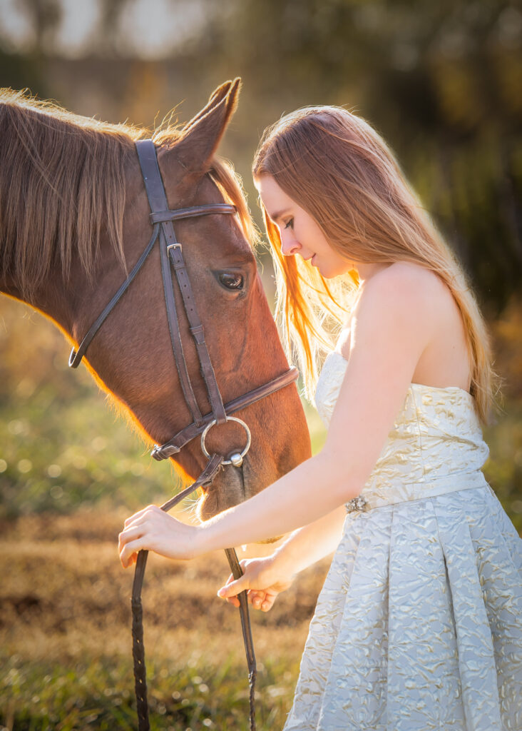 Women holding the reigns of her horse in the sunset