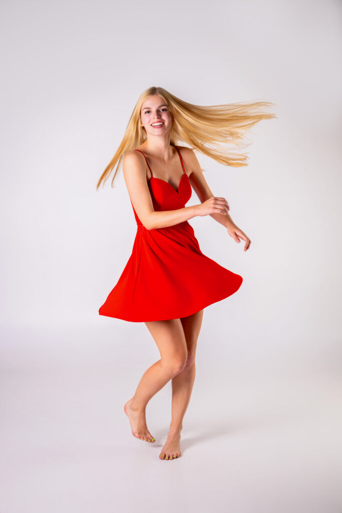 High school senior in red dress spinning around