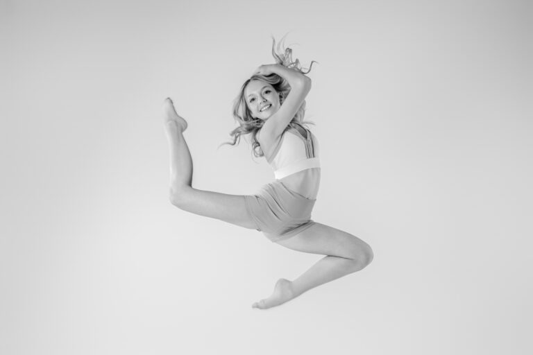 A young dancer in black and white jumping into the air