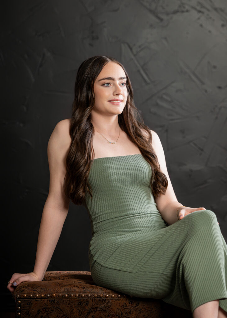 Female high school senior in green dress smiling to the side in candid