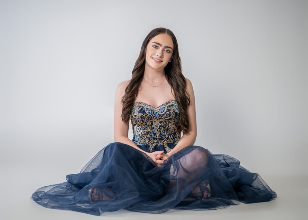 Female high school senior in her ballgown sitting on the floor in studio